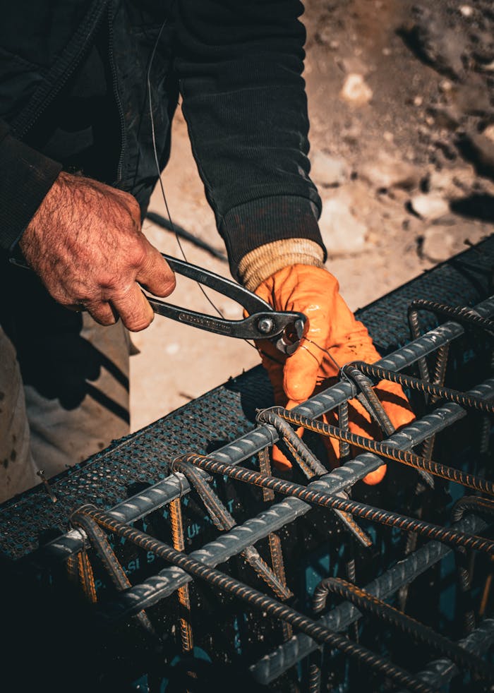 Close-up of a construction worker tightening rebar with a wrench, showcasing manual labor.